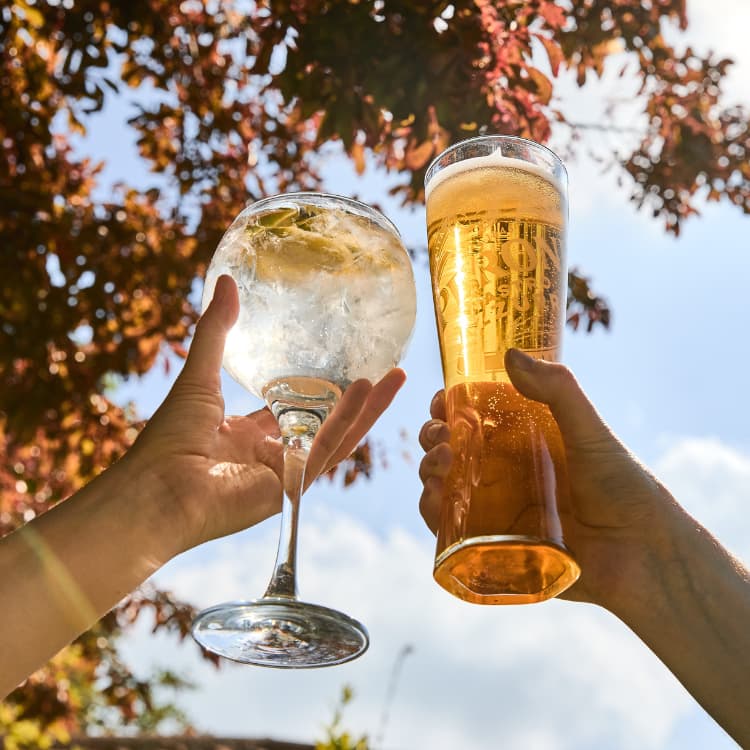 A pint of beer and a cocktail outside on a sunny day