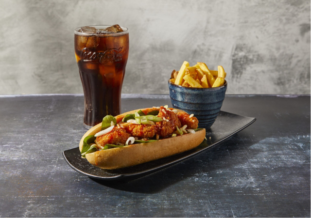 Image of chicken sub sandwich, fries and a glass of coke of a grey backdrop Image of chicken sub sandwich, fries and a glass of coke of a grey backdrop